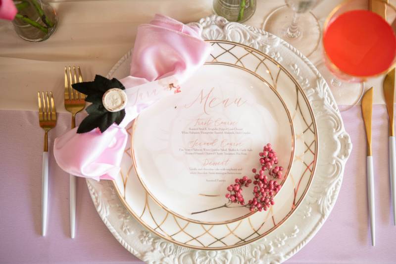 Place setting flat lay with gold cutlery and pink napkin 