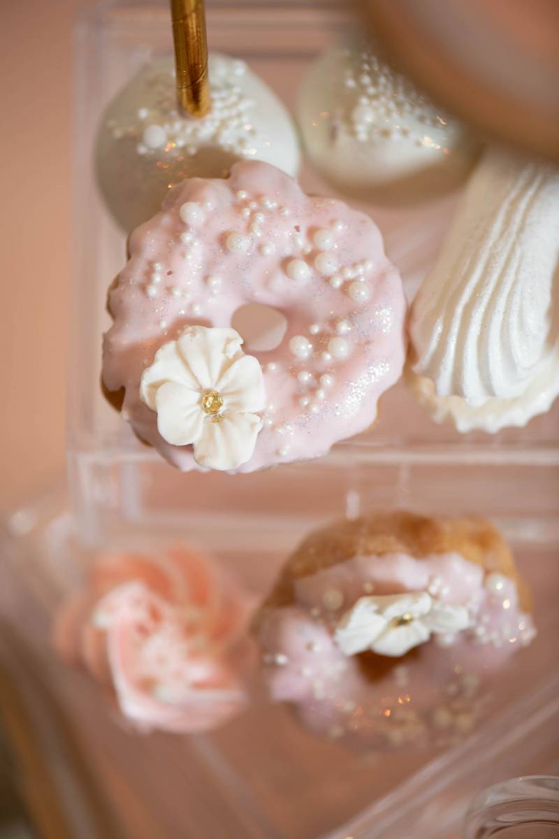 Pink frosted mini doughnut beside white cake pops 