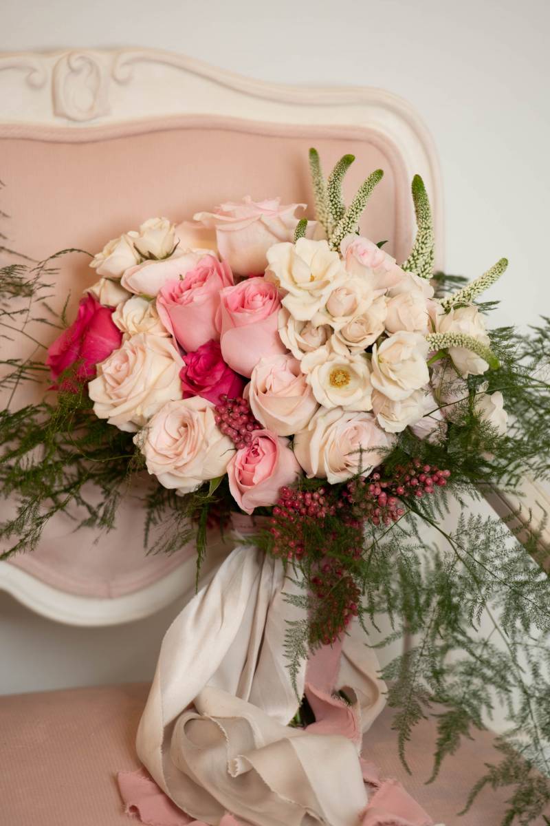 Pink white and red floral arrangement on pink chair 