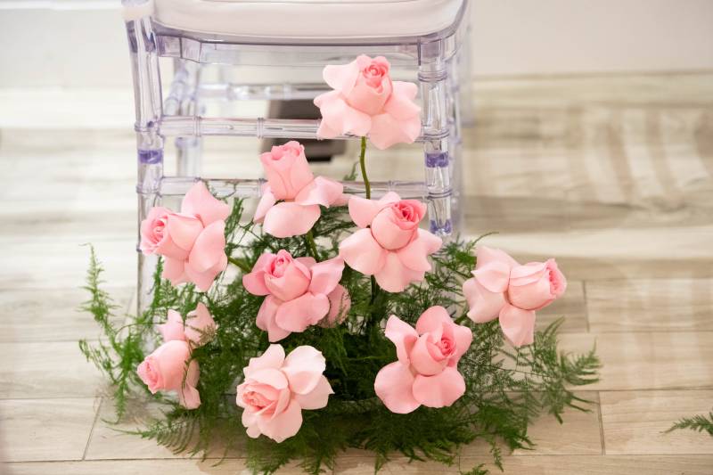 Pink flowers at edge of clear framed seat with white cushions 