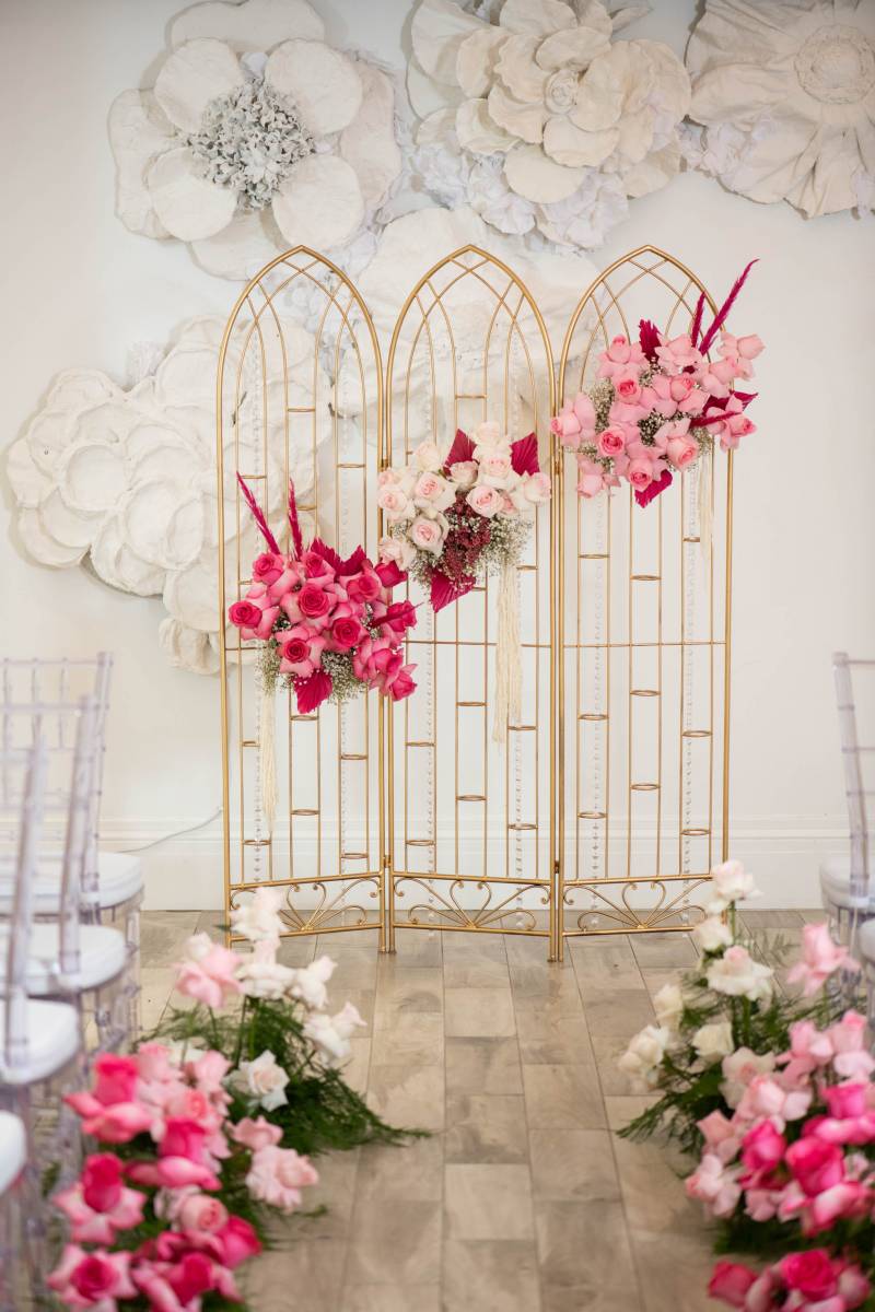 Gold folding arches with pink and white flowers diagonal across them 