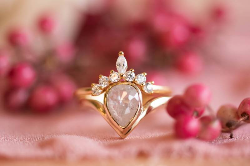 Asymmetric gold band wedding ring beside pink berries  