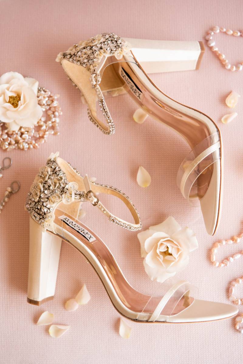 Cream colored heels laying on blush pink surface 