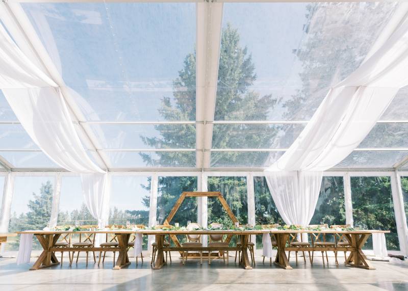 Outdoor tent wedding reception table with octagonal wedding arch behind wooden table
