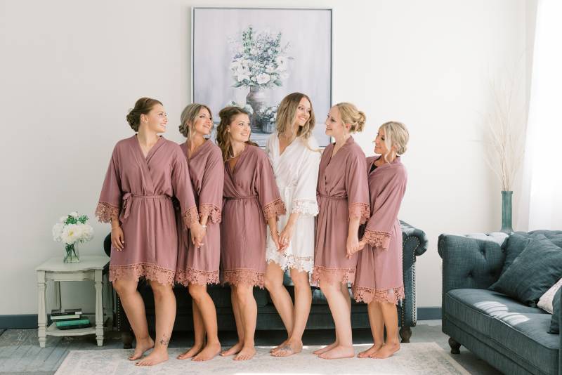 Bride and bridesmaids stand together in kimonos in living room 