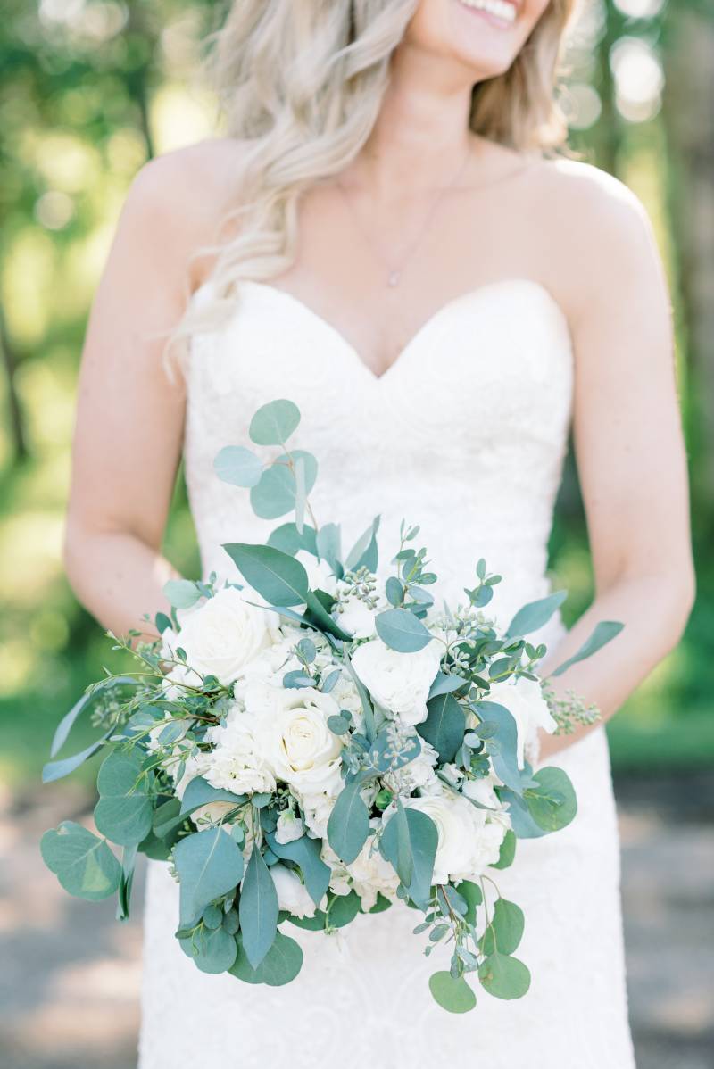 Bride smiling holding white bouquet in front 