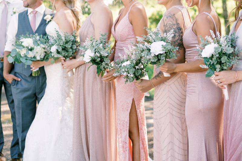 Bridesmaids standing in line holding white bouquets